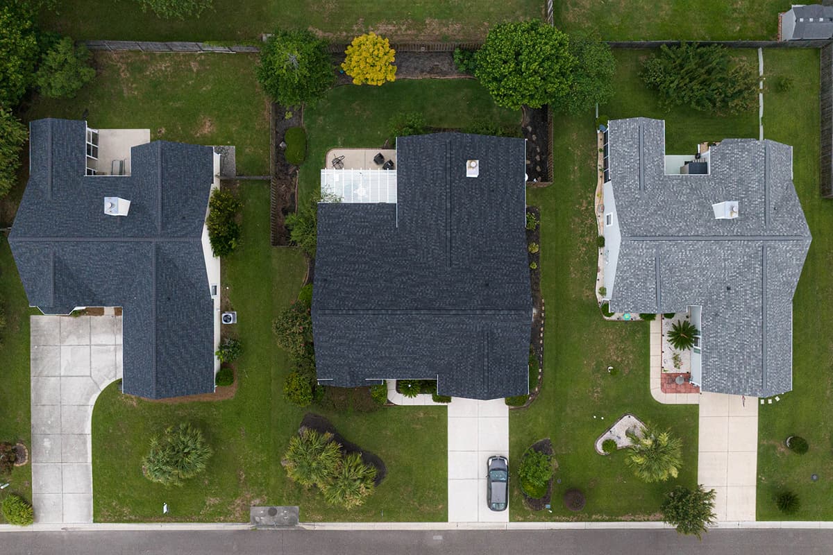 Aerial view of three neighboring homes with asphalt shingle roofs