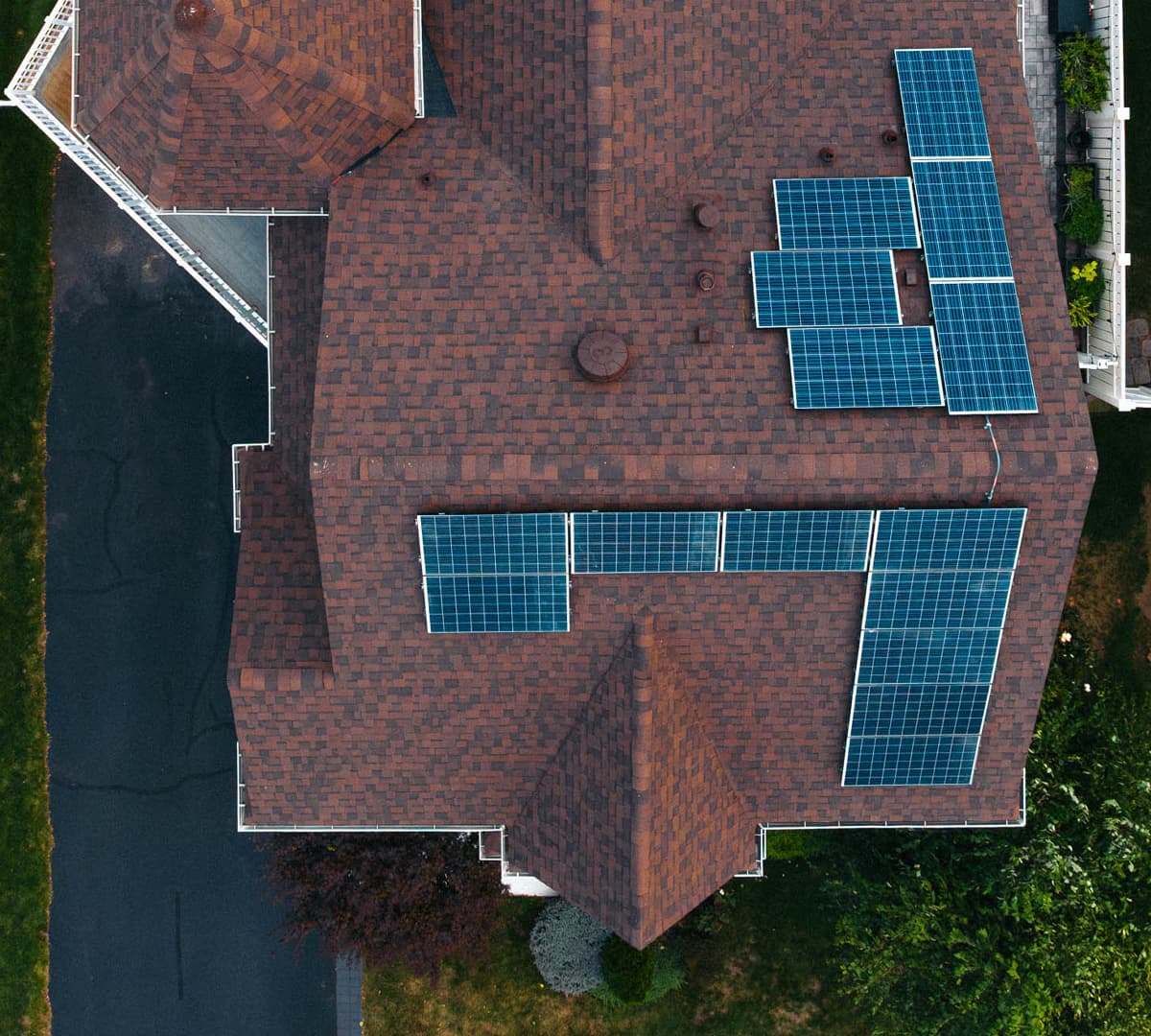 Overhead view of a shingle roof with several solar panel arrays
